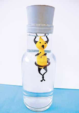 Setze das Flaschenteuferl in eine randvoll mit Wasser gefüllte Flasche, verschließe sie mit einer Gummikappe und drücke dann auf die Kappe.