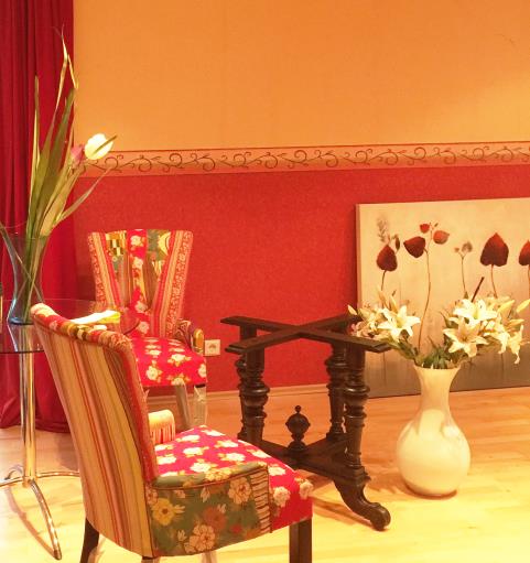 Im sonnigen Wohnzimmer platzieren wir ein farblich harmonierendes Sofa und tolle rotgeblümte Sessel.