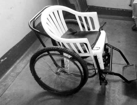 Ein ghanaischer Rollstuhl Patienten, die nicht aufrecht sitzen konnten, legten sich aus Mangel an Krankenbetten auf die Holzbänke im Wartesaal hin und wurden dann dort behandelt.