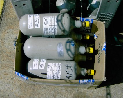 Beispiele für ungeeignete Ladungssicherungssysteme für die Beförderung kleiner Druckgefäße Die oberste Flasche kann aus dem Karton herausfallen. Ein Ventilschutz ist hier nicht gegeben.
