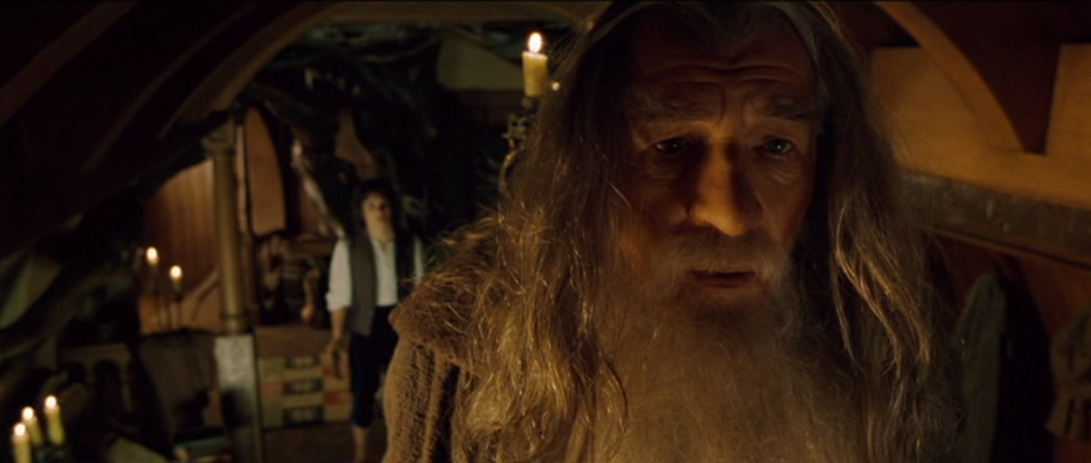 Gandalf hebt einen Briefumschlag hin, Frodo lässt den Ring hineinfallen, Gandalf versiegelt den Umschlag und gibt ihn Frodo und sagt: Tu ihn irgenwo hin, wo ihn niemand