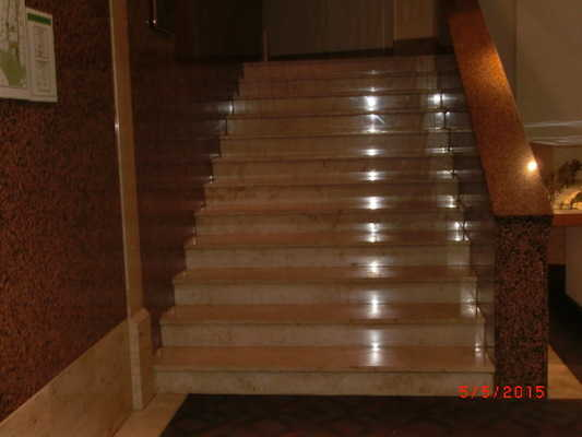 Visueller Kontrast zwischen Fußbodenbelag und Treppenauf- und -abgang. Treppe hell und blendfrei ausgeleuchtet.