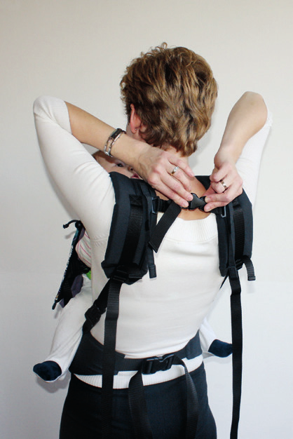 Bring first shoulder strap over the shoulder while holding your baby with the other hand.