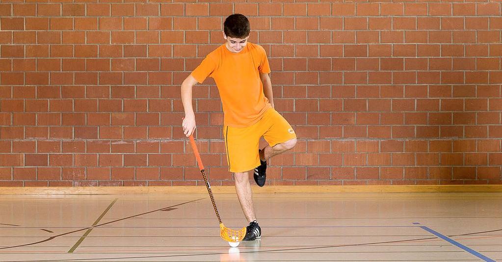 Unihockey-Flamingo Stehe auf ein Bein und führe den Unihockeyball um dein Bein herum.