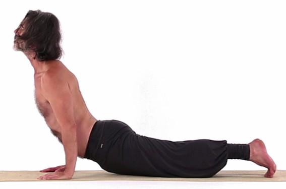 Die Spitze des Steißbeines bewegt sich in einer gleitenden Bewegung, sie folgt dabei einer zentralen Linie auf der Yogamatte.