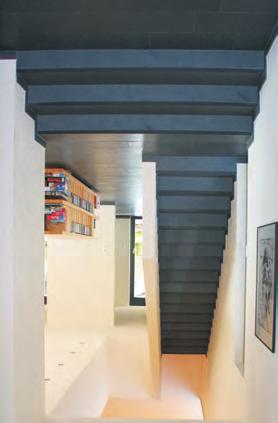 Wie das Rückgrat des Hauses wirkt diese Treppe. Sie ist, wie der Fußboden des Wohnbereichs, mit Schieferplatten belegt. Wer sparen will: Sichtbeton wäre auch eine gute Wahl.
