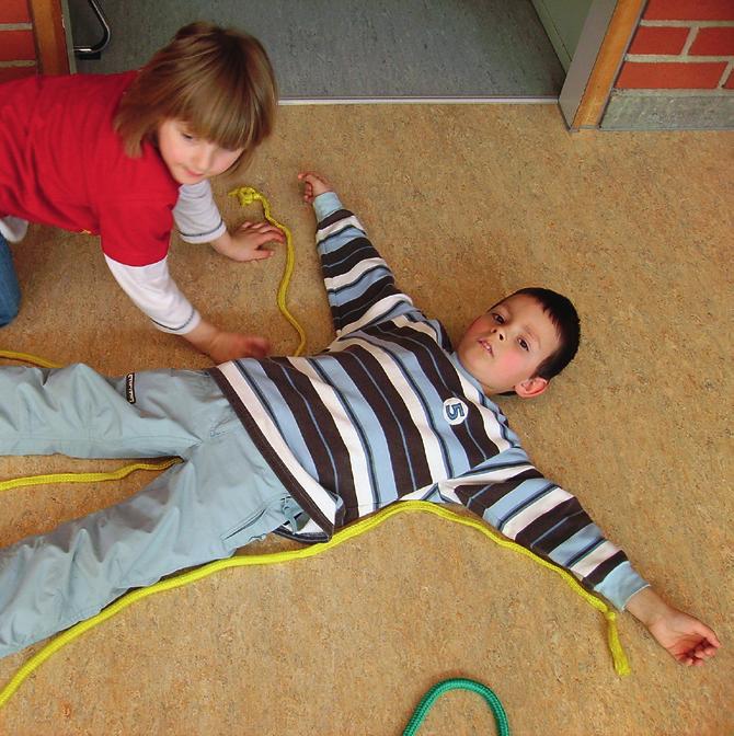 Körperumrisse legen Demonstrieren: 1 Kind liegt, 1 2 weitere legen eng um dessen Körper Seilchen linienförmig herum. Kind steht auf, Umriss bleibt liegen.