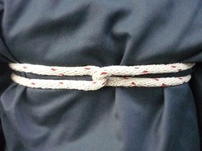 Das Seil wird so über die Schultern der betroffenen Person gelegt, dass das kurze Seilende bis auf den Boden reicht.