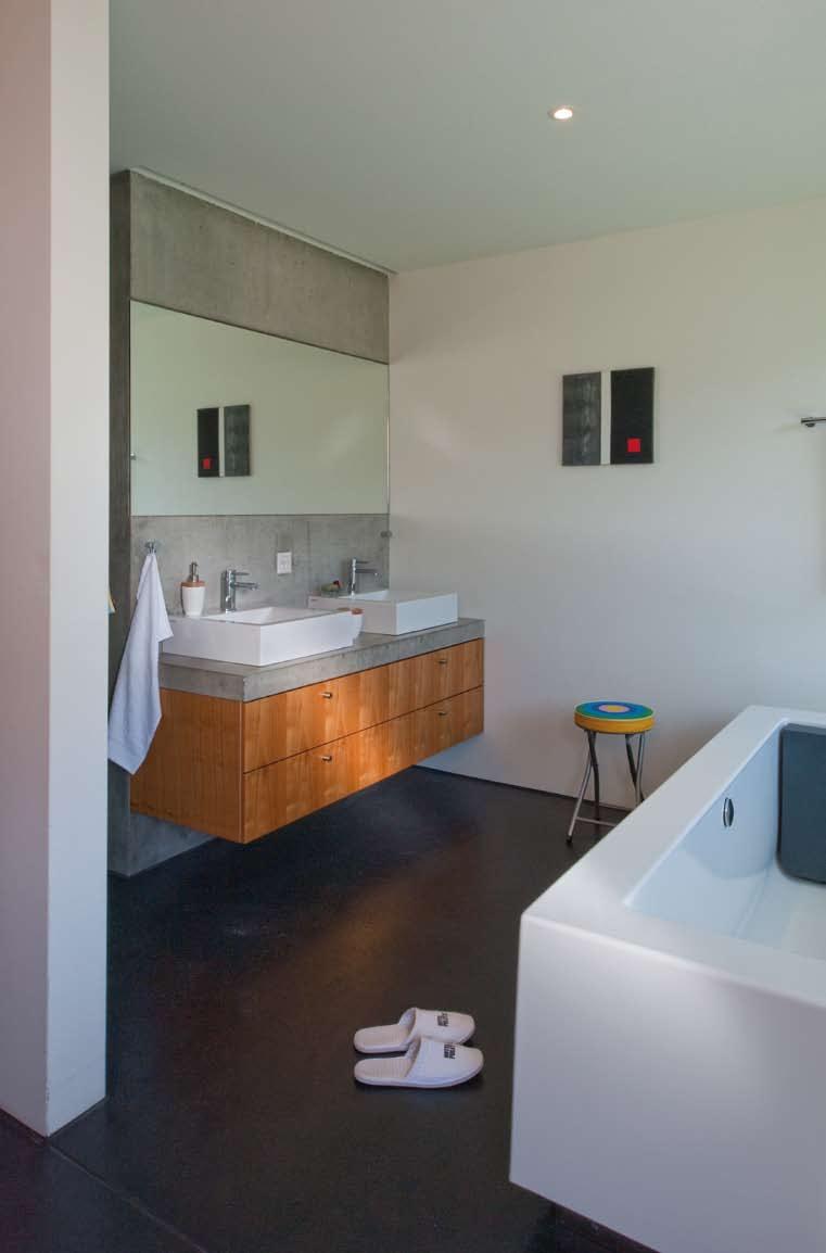 ARCHITEKTUR Solothurn _Das offenen Bad neben dem Schlafzimmer. _Auch im Bad trifft man auf Sichtbeton und einen anthrazit eingefärbten Unterlagsboden. Der Waschtischkorpus besteht aus Kirschbaum.