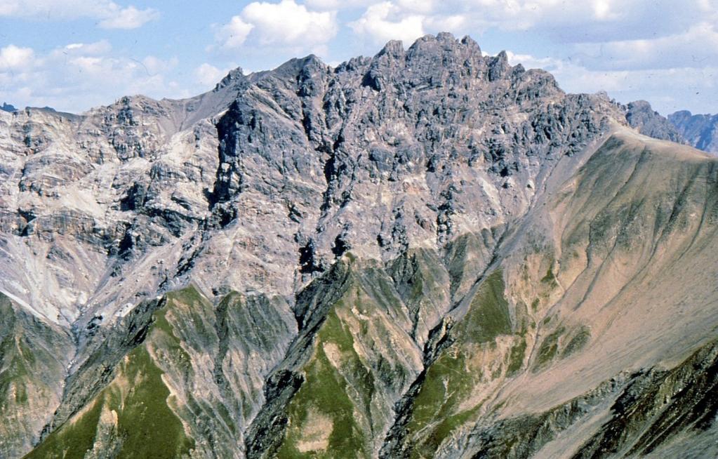 Darunter liegen in verkehrter Lagerung Reste der ehemaligen Bedeckung des Grundgebirges; das auffallende helle Band ist Trias-Dolomit. Es handelt sich also um eine Faltendecke mit Verkehrtschenkel.