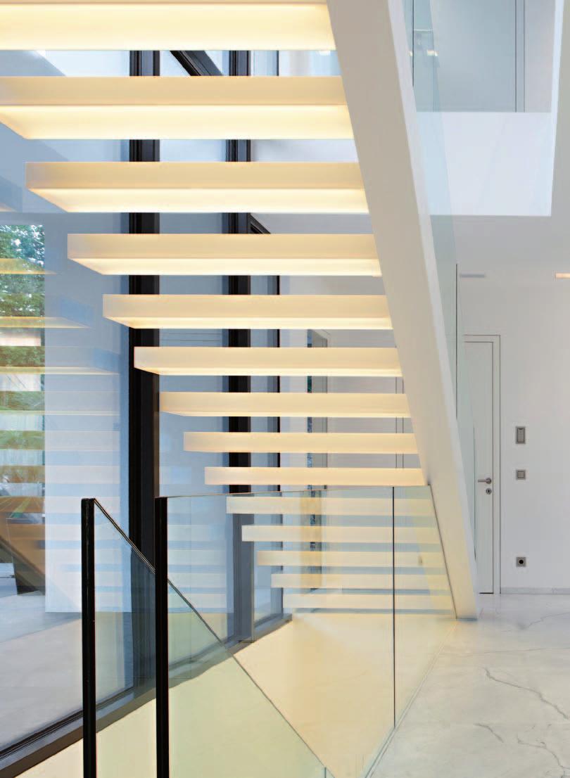 Massive und transparente Flächen verleihen dem kompakten Baukörper der Villa Leichtigkeit. Ein Blickfang innen wie außen ist die nach oben schwebende Treppe, die über LEDs in Szene gesetzt wird.