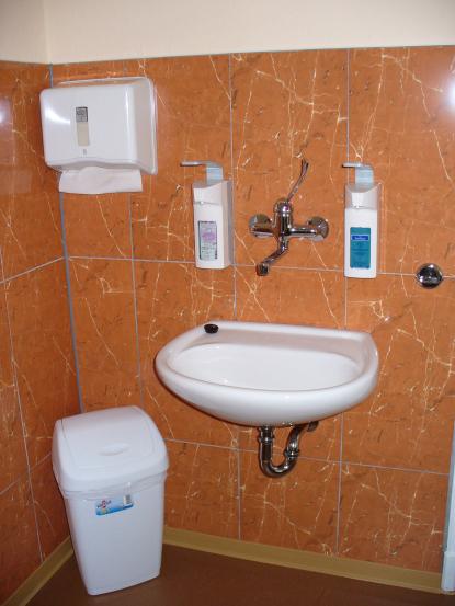 Handwaschbecken im Behandlungsraum (komplett nach TRBA 250: fließend kaltes und warmes Wasser, Armatur, die eine Handgelenkbedienung ermöglicht, Spender für Händedesinfektionsmittel, Flüssigseife und