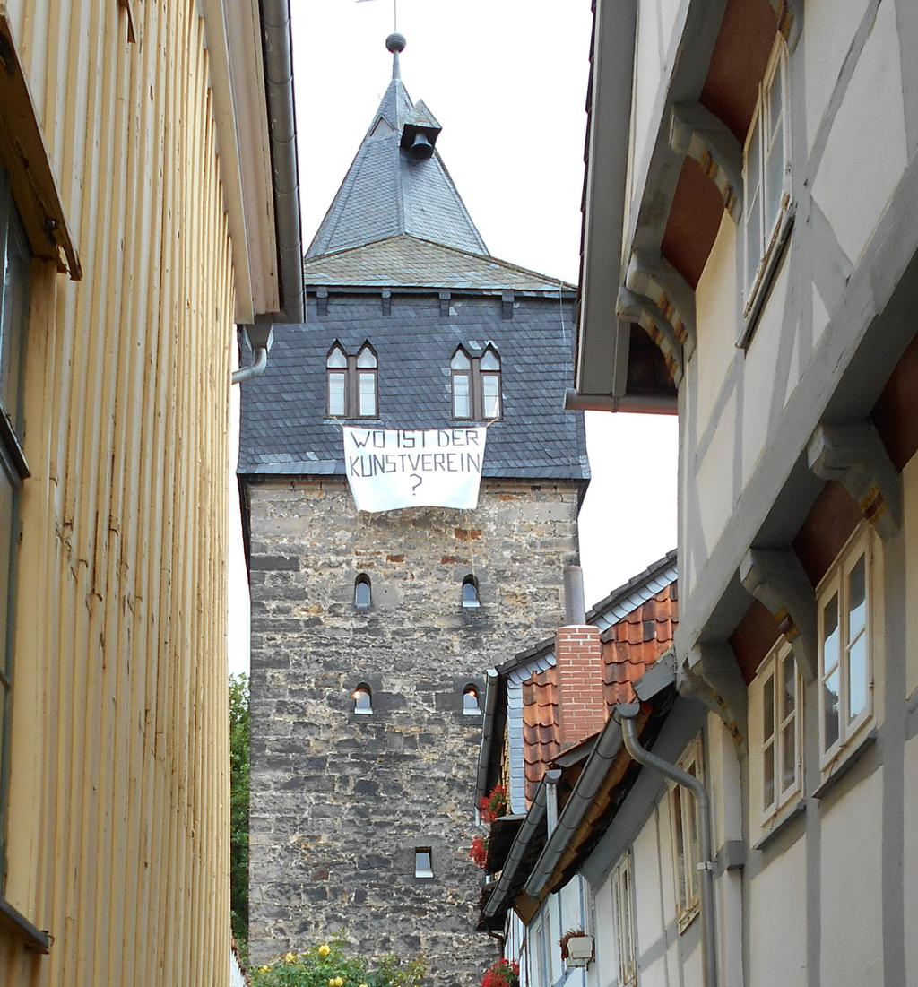 Aus den Fenstern des Kehrwiederturms werden Banner gehängt, die Fragen zeigen zur Rolle des Kunstvereins und zum städtischen Leben in Hildesheim.
