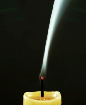 Flammensprung Eine Kerze wird, nachdem sie ein paar Minuten gebrannt hat, mit angefeuchtetem Daumen und Zeigefinger gelöscht.