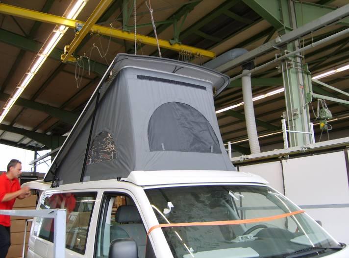 Anschließend wird das Schlafdach auf das Fahrzeug aufgesetzt und an den Konturen der Windschutzscheibe sowie an der seitlichen Regenrinne ausgerichtet.