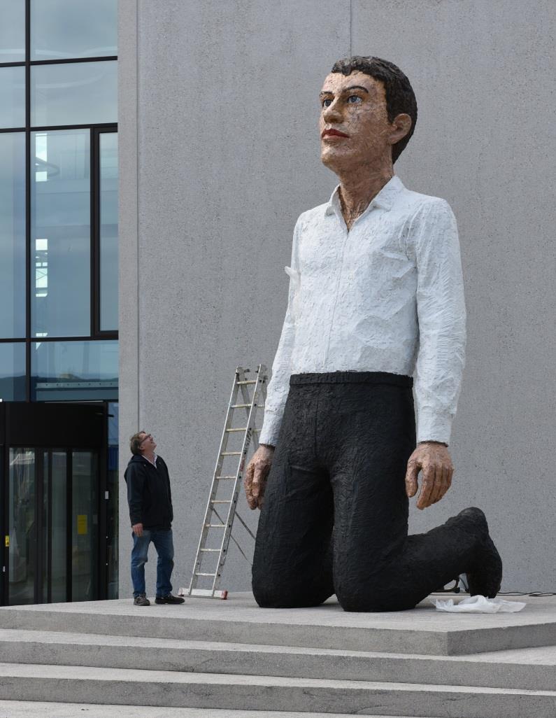 Bild 3: Die Skulptur kniet vor dem Schulungs- und Ausstellungszentrum, Hörmann Forum, mit aufrechter Haltung, erhobenem Kopf und den Blick erwartungsvoll in die