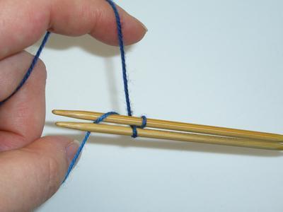 Bring needle #2 over the yarn tail on your thumb, around and under the yarn and back up, making a loop around needle #2. Pull the loop snug around the needle. Youhavecastonestitchontoneedle#2.