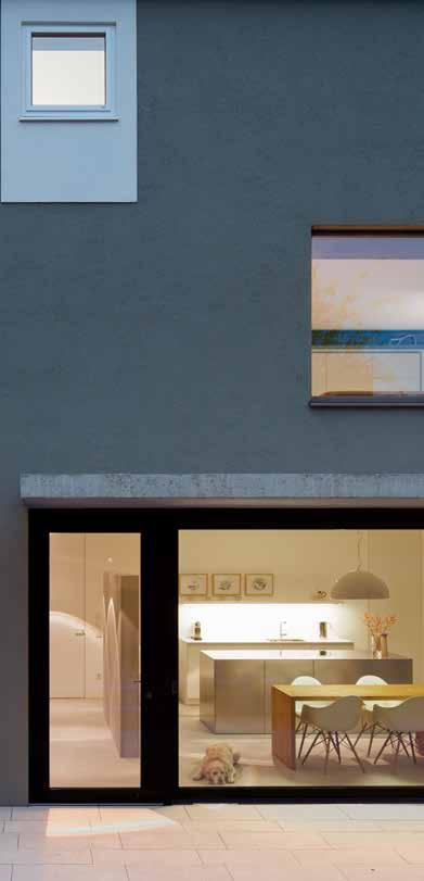 Fassadendetail mit Einblicken in Küche, Wohnraum und Schlafgeschoss. Markant ist die unterschiedliche Rahmung der Fenster. Die Küche der Architekten öffnet sich zum Terrassenhof.