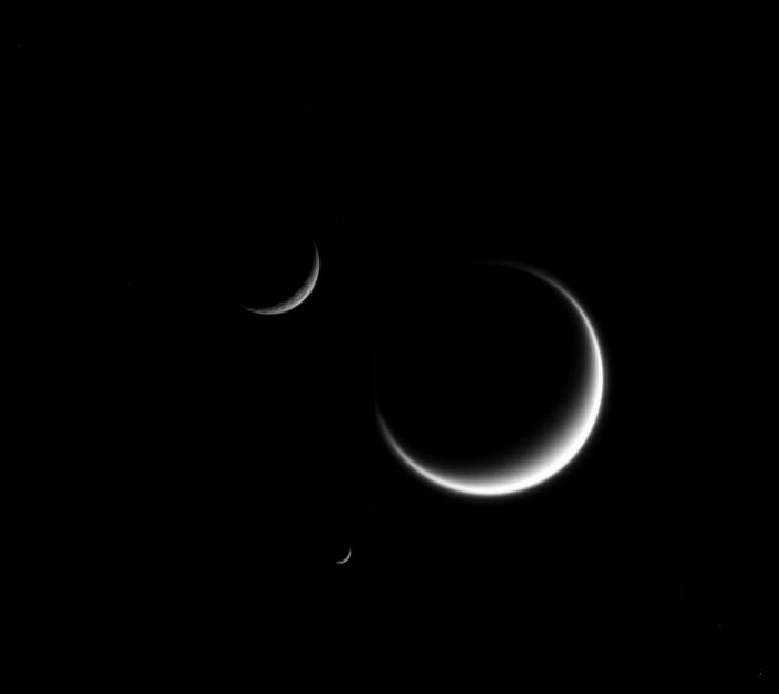 Drei sichelförmige Saturnmonde: Rhea, Titan, Mimas Titan wirkt verschwommen, wegen seiner dunstigen, dichten Atmosphäre, die das
