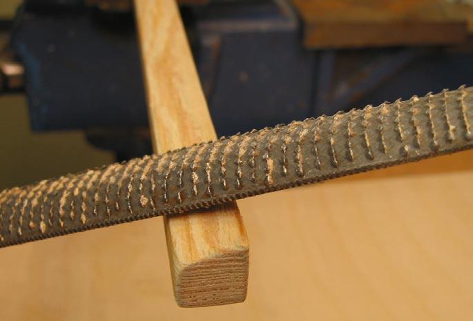 Die oben mittig verstärkte Holzleiste wird mit der Raspel oder mit der Schleifmaschine jeweils leicht angeschrägt, jede Seite in die