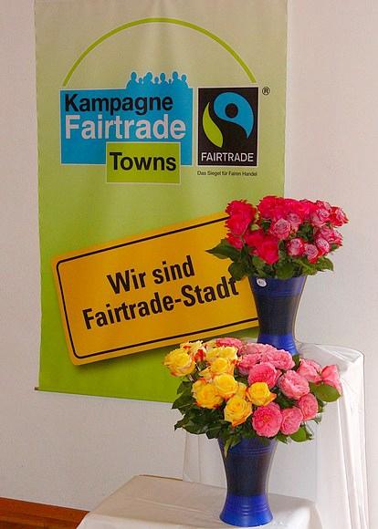 Das Plakat gibt es schon einmal bekannt: Wir sind Fairtrade-Stadt, wo es auch faire Rosen zu kaufen gibt.