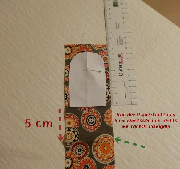 Das Papier-Schnittmuster auf den Streifen stecken, oben genügend Nahtzugabe lassen, die auseinandergebügelte Wendenaht liegt unter dem Papier.