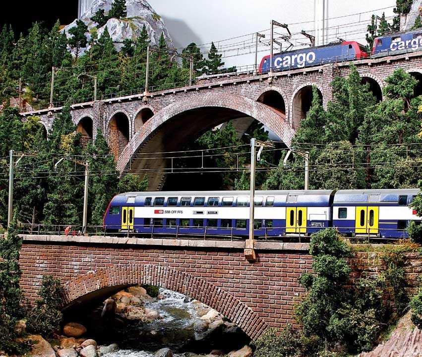 Die modernen Züge setzen sich auf dem Steinviadukten farblich gegen die Vegetation auf dem
