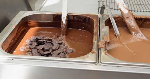 Dazu kommen einige dunkle Schoggirondos. Diese sind nötig, damit die Schokoladenmasse nach dem Abkühlen ihre glänzende Oberfläche behält. Der Vorgang wird als «Impfen» bezeichnet.