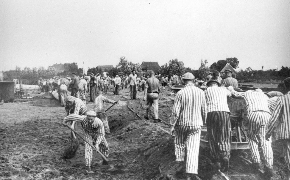 Erdarbeiten an der Dove Elbe, im Hintergrund Bauernhäuser des Dorfes. In der Mitte ein Kapo zur Bewachung.