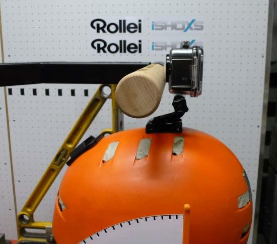 Prüfung: Durch den Aufschlag auf das auf einem Helm an einem Halter befestigte Kameragehäuse wird auf den drehbar gelagerten Helm ein Drehimpuls ausgeübt.
