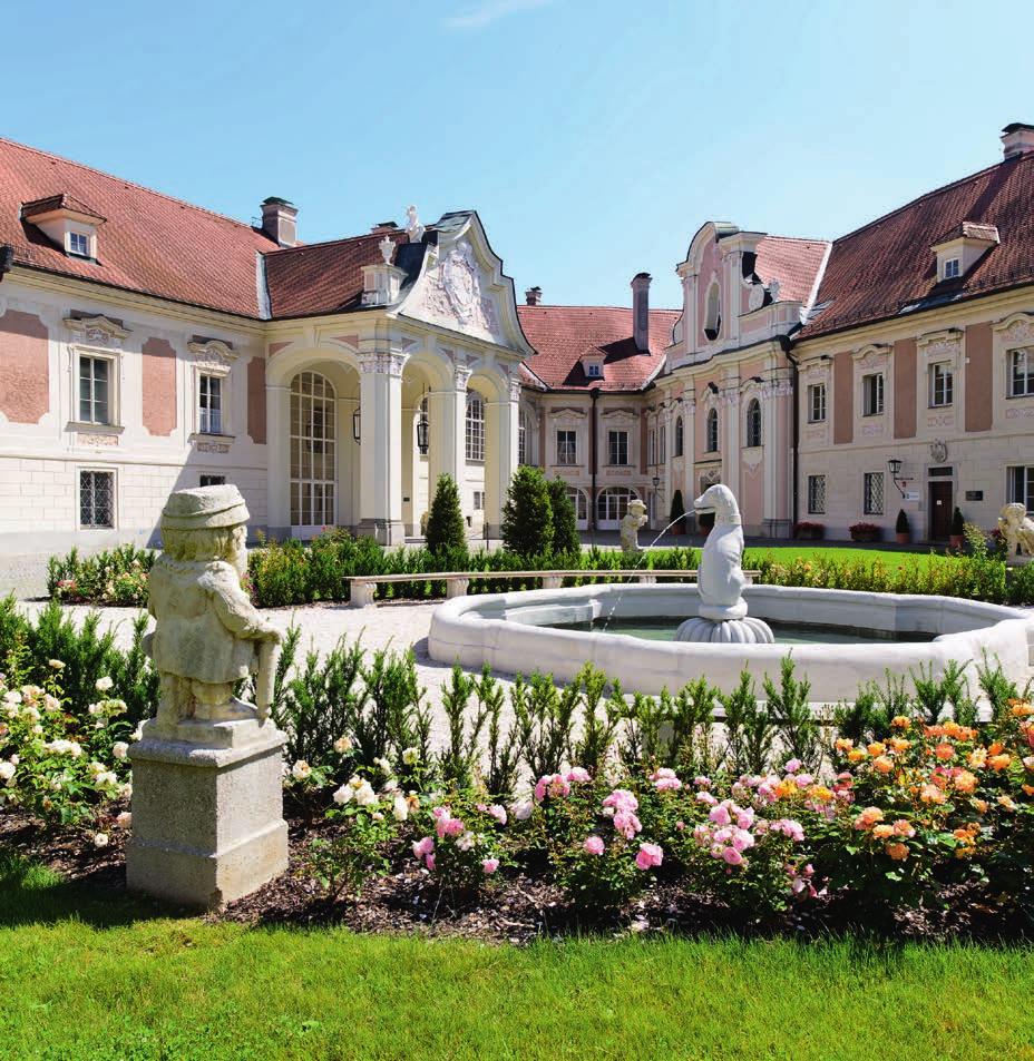 Der begrünte Schlosshof wird rundum von barocken Fassaden eingerahmt mitten drinnen ein historischer Brunnen mit Zwergen aus Sandstein und einem Hund, dem Wappentier der Lamberger.