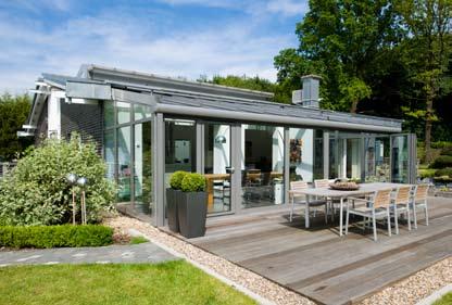 Großflächige Glas-Faltwände öffnen den transparenten Anbau zum Garten hin und schaffen fließende Übergänge.