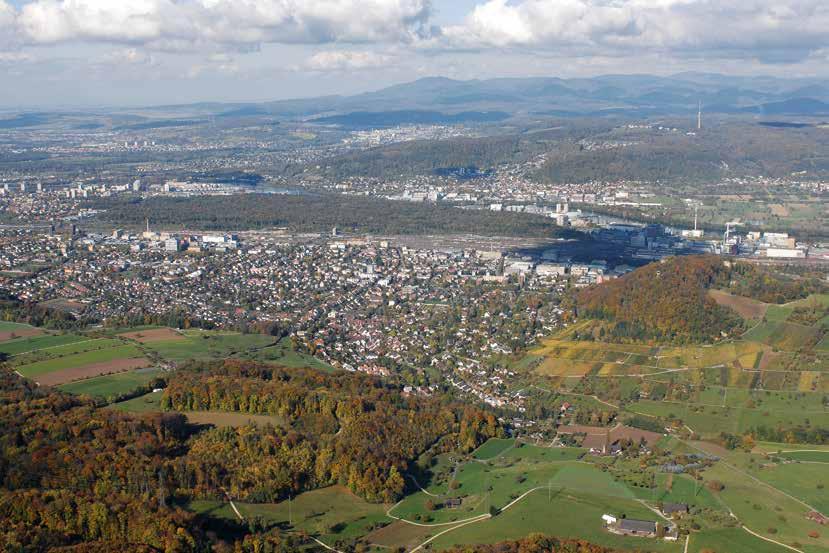 70 5 Geispel 96 Muttenz (Kt. BaselLandschaft), Flugaufnahme von Südosten mit der Freilandsiedlung Geispel (Punkt) und der dicht überbauten Rheinebene.