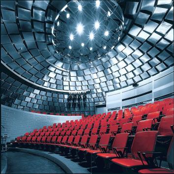 Im Untergeschoss ruht das rote, kuppelförmige Auditorium in einem Wasserbecken: Ein Hinweis auf die Bedeutung der zwei wichtigsten Elemente beim Drucken: Farbe und Wasser.