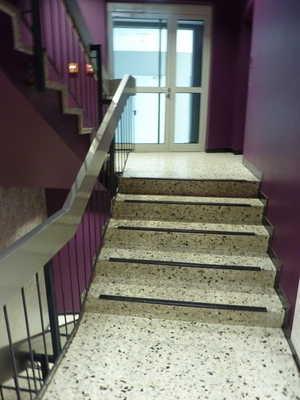 Die Treppe hat einen einseitigen Handlauf. Die Handläufe werden am Anfang und am Ende der Treppenläufe mehr als 28 cm waagerecht weitergeführt.