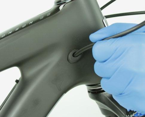 Bauen Sie die Sattelstütze in den Fahrradrahmen ein, während Sie vorsichtig die Hydraulikleitung aus der Leitungsführungsöffnung im Rahmen