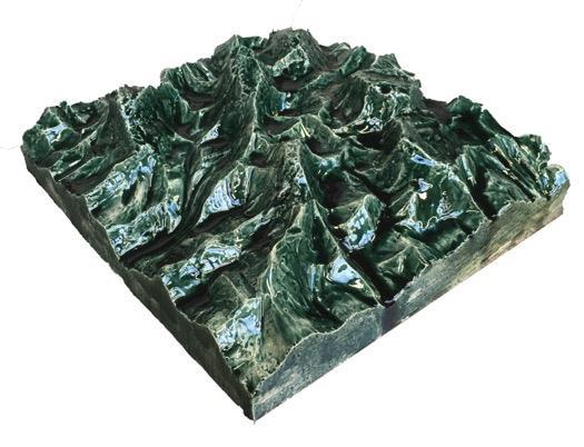 Durch die grün-blaue hochglänzende Oberfläche der Glasur variiert die Wahrnehmung von einer Bergwelt mit Seen bis hin zur aufgewühlten Wasseroberfläche.