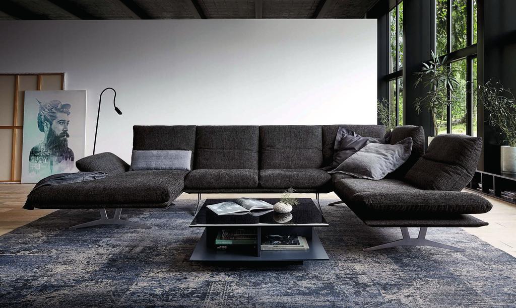 Fast scheint dieses formschöne Sofa zu schweben, fußt es doch auf elegant geschwungenen Kufen, die für ungewöhnliche Bodenfreiheit und überraschenden Durchblick sorgen.