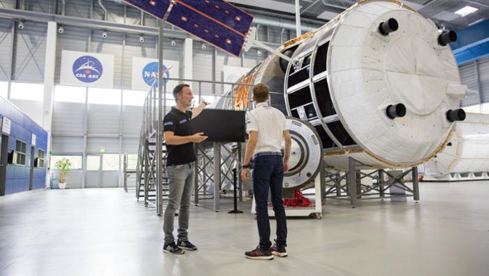 Matthias Maurer führt Timo Bernhard durch das Astronautenausbildungszentrum Nach dem gescheiterten Boxenstopp im Weltall am Simulator steigen Raumfahrer und Rennfahrer ins Columbus-Modul der ISS, das