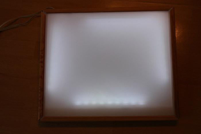 Die Glasplatte wird auf den Kasten gelegt, die Leisten auf der innen Seite die am Holzkasten ist (nicht die Seite die auf die Glasplatte drückt) werden mit Leim versehen und ebenfalls mit kleinen