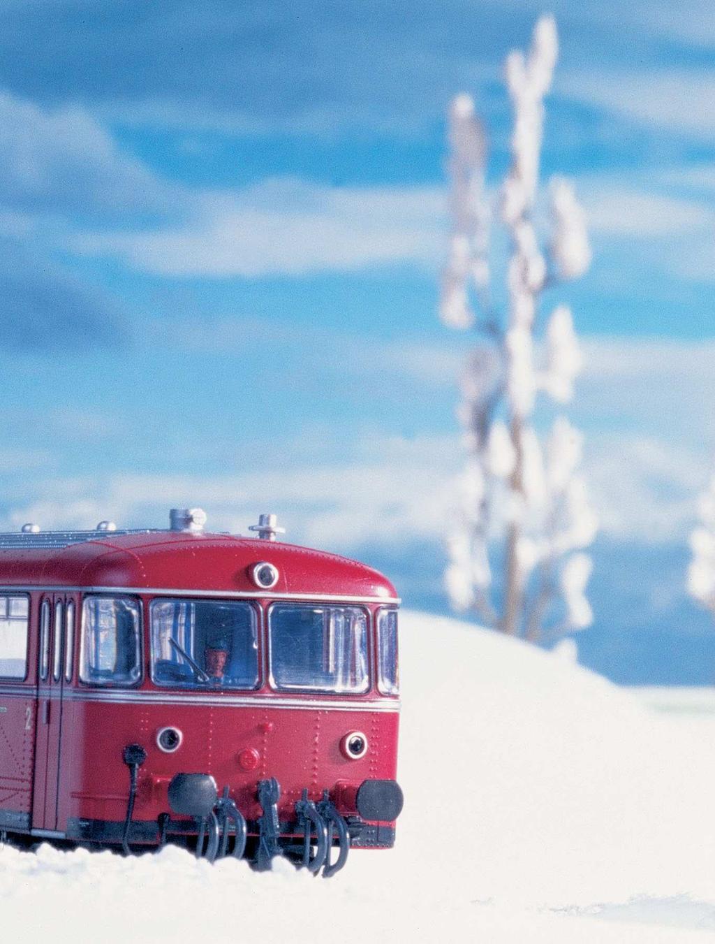 Pulverschnee bedeckt die Landschaft mit einem herrlich weißen Mantel Bei tiefstehender Wintersonne braust ein roter Schienenbus durch
