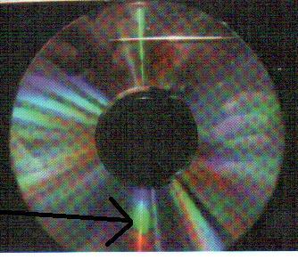 die andere Hand hält einen CD-Rohling. Idealer Weise fällt das Licht der Sonne nur auf die Nadel und von dort auf die CD. Dunkle Kleidung hilft, Streulicht zu vermeiden.