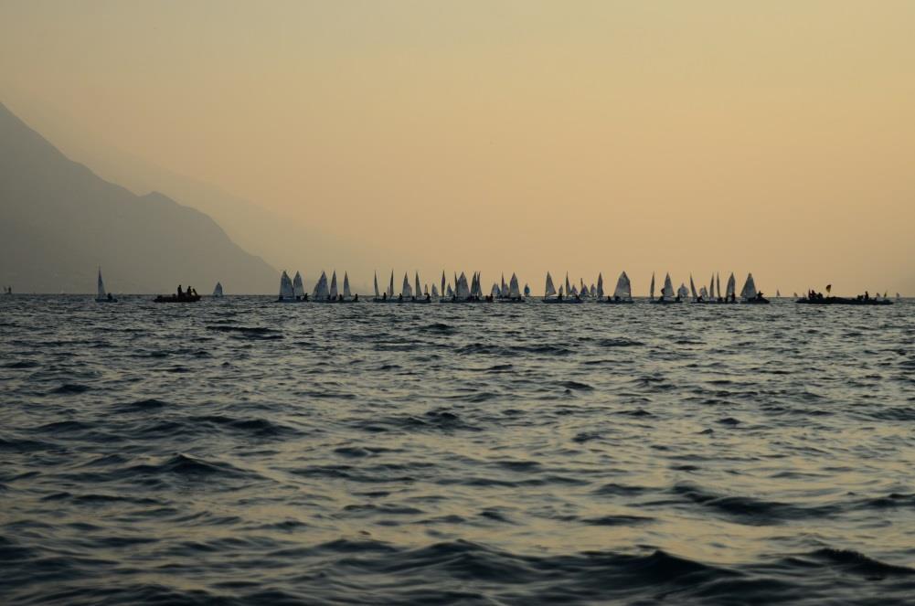 Im Vordergrund segeln drei Boote aus Schweden, was an dem Segelzeichen SWE zu erkennen ist. Nicht immer ist der Gardasee so ruhig wie hier.