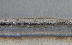 Entlang der Fügelinie des Hochmanganstahls bei der Schw eißung, die mit dem CrNi-Zusatz erzeugt w urde, ist eine schmale Schmauchspur zu erkennen.
