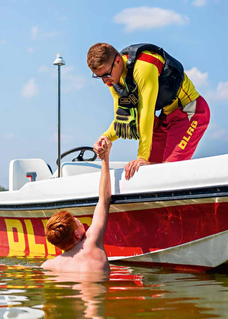 Ein DLRG- Wasserretter hilft einem entkräfteten Schwimmer ins Motorrettungsboot nur einer von