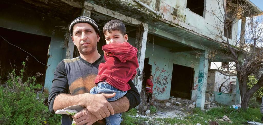 SYRIEN + + DER KRIEG FINDET KEIN ENDE Ein Vater mit seinem Sohn im Dorf Khan Jouz. Im Hintergrund die ausgebrannte Ruine seines von der al-nusra-front zerstörten Wohnhauses.