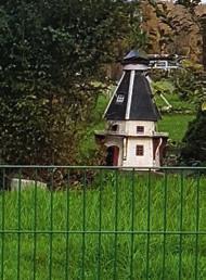 Weiter rechts fällt der Blick auf eine kleine Windmühle (F), die etwas abseits im Garten