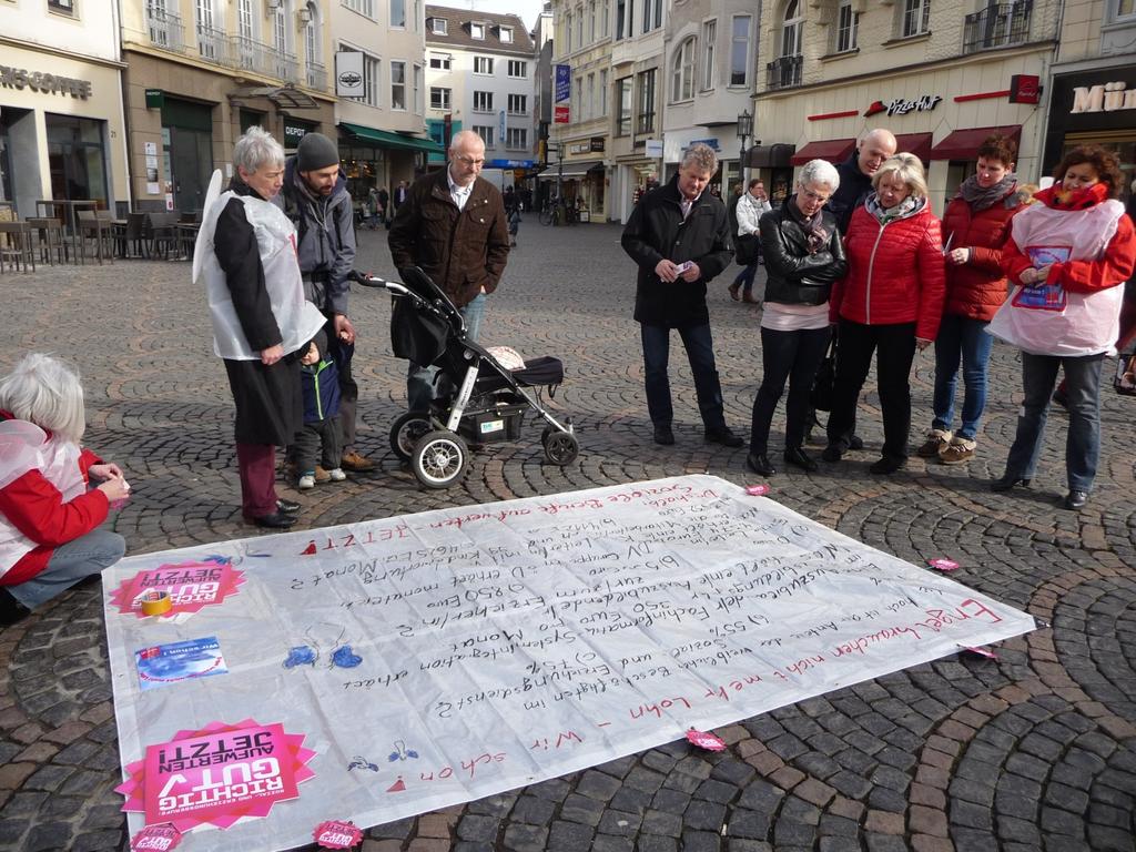 (Bodenzeitungen in der Bonner Fußgängerzone machen neugierig (Foto: Barbara Henke)) Der gemeinsame Roll Up mit den Slogans aller beteiligten Organisationen am IFT wird beim Empfang des