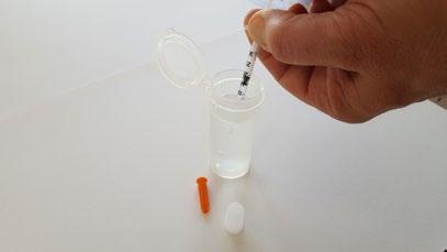 Entnahme der Probe aus der Wasserquelle mit dem steril verpackten Kunststoffbecher Der Wasser-Schnelltest