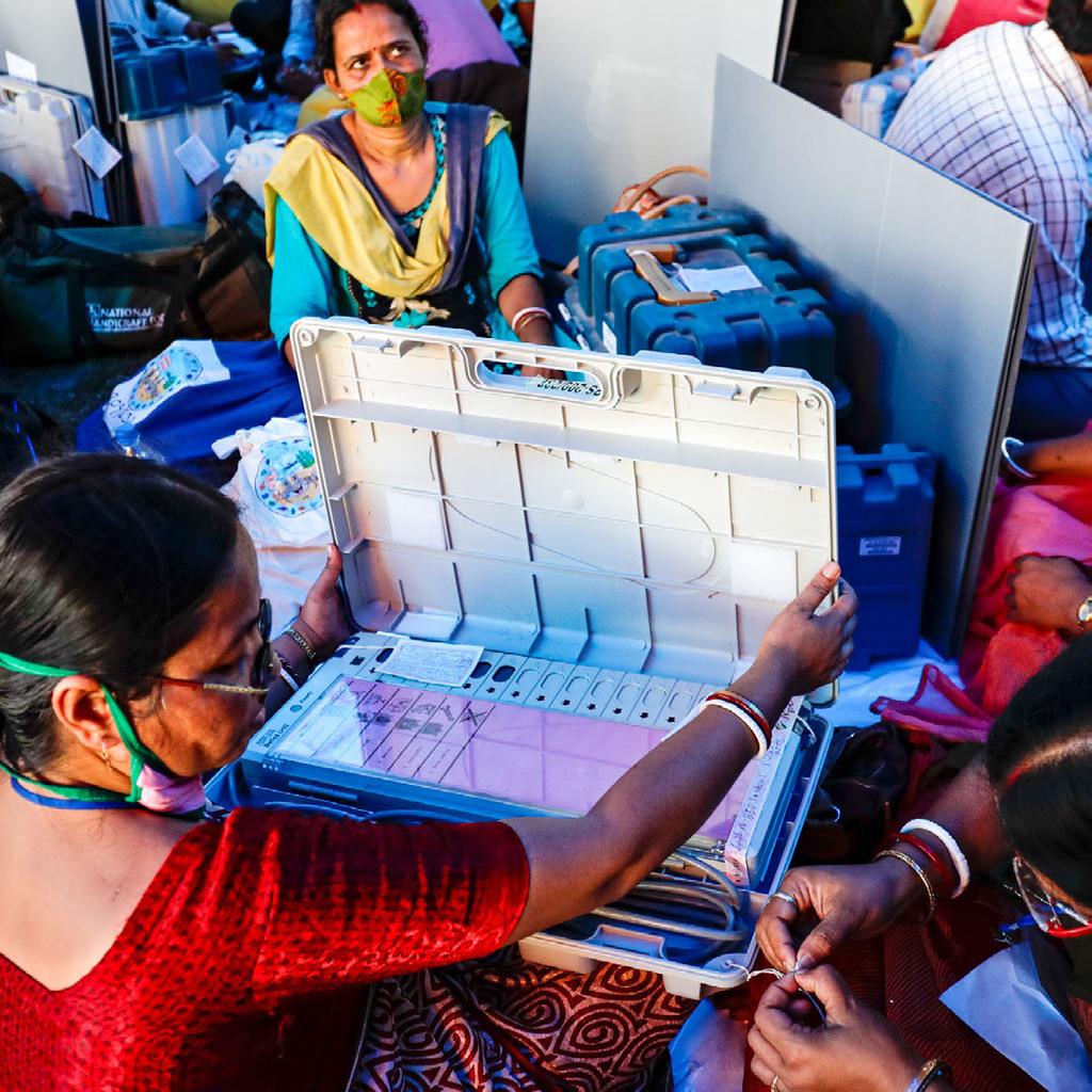 18 Wahlhelferinnen überprüfen elektronische Abstimmungsgeräte, bevor sie zu ihren Wahllokalen